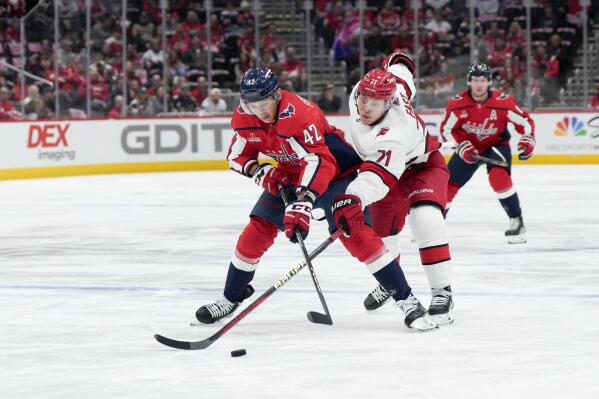 Washington Capitals defenseman Martin Fehervary (42) and Carolina Hurricanes right wing Jesper Fast (71) reach for the puck during the first period of an NHL hockey game, Tuesday, Feb. 14, 2023, in Washington. (AP Photo/Jess Rapfogel)