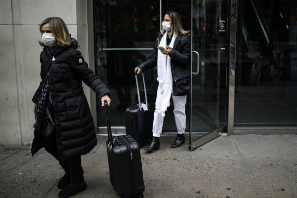Shoppers wear face masks as they walk in New York's Herald Square on Thursday, March 12, 2020. Mayor Bill de Blasio said Thursday he will announce new restrictions on gatherings to halt the spread of the new coronavirus in the coming days, but he hopes to avoid closing all public events such as Broadway shows. (AP Photo/John Minchillo)