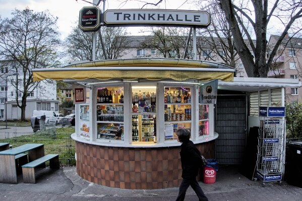 A woman walks past a former water house, a small shop that sprung up in the 19th century to encourage workers to drink affordable water rather than beer or schnapps, that is now a kiosk in Frankfurt, Germany, on March 31, 2025. (AP Photo/Michael Probst)