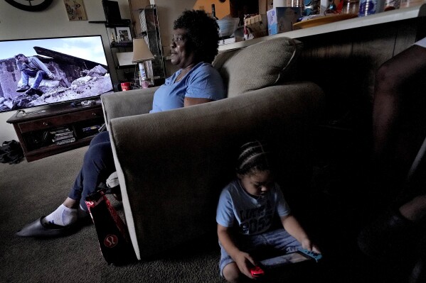 Bobbie Boyd sits in her apartment with her three-year-old grandson DeAngelo Boyd, Wednesday, Aug. 9, 2023, in Fayetteville, Ark. On a fixed income, Boyd sacrifices meals, health care, and car insurance among other necessities to pay rent and keep cool in the midst of this summer's prolonged heat waves. (AP Photo/Charlie Riedel)