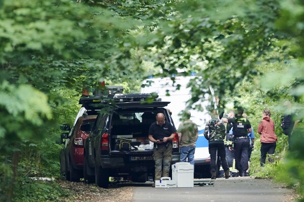 Animal experts and police officers stand in a wooded area in Berlin's Zehlendorf district, Germany, Thursday, July 20, 2023. German police are searching with helicopters, drones and infrared cameras as well as a vet and hunters for a potentially dangerous animal, suspected to be a lioness, that was sighted overnight on the southern edge of Berlin. (Annette Riedl/dpa via AP)