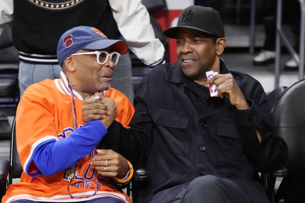 FILE - Actor Denzel Washington, right, shakes hands with director Spike Lee before an NBA basketball game between the Los Angeles Lakers and the New York Knick in Los Angeles on March 12, 2023. Nearly 20 years after their last collaboration, Lee and Washington are reuniting for an adaptation of Akira Kurosawa’s “High and Low.” (AP Photo/Marcio Jose Sanchez, File)