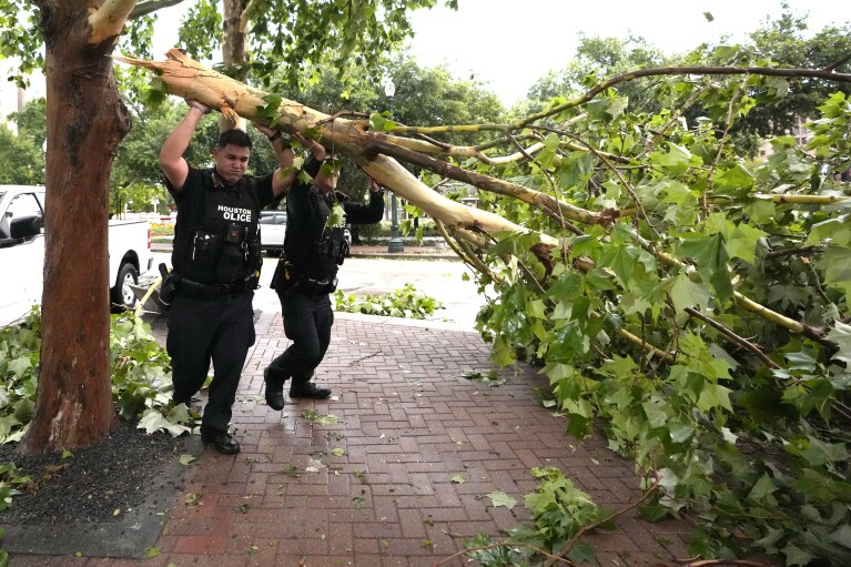 Politieagenten uit Houston verwijderen een omgevallen boom in Prairie en Travis Streets in het centrum na zware onweersbuien op donderdag 16 mei 2024 in Houston.  (AP via Karen Warren/Houston Chronicle)