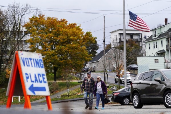Voter arrive at a polling place at the Gov. James B. Longley Campus, Tuesday, Nov. 7, 2023, in Lewiston, Maine. The American flag still flies at half mast in honor of the 18 people who were killed in mass shootings less than two weeks ago. (AP Photo/Robert F. Bukaty)