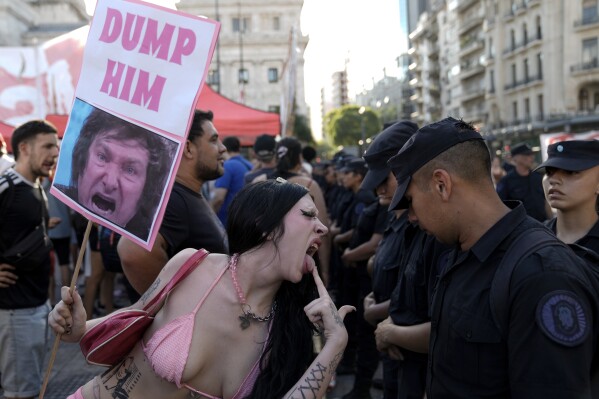 An anti-government protester taunts police guarding Congress where lawmakers are debating a bill promoted by Argentine President Javier Milei, in Buenos Aires, Argentina, Thursday, Feb. 1, 2024. The bill includes a broad range of economic, administrative, criminal and environmental reforms. (AP Photo/Rodrigo Abd)