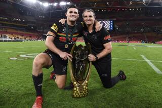 Nathan Cleary, left, and Ivan Cleary of the Penrith Panthers pose for a photograph following the National Rugby League grand final between the Panthers and South Sydney Rabbitohs in Brisbane, Sunday, Oct. 3, 2021. Ivan won a NRL grand final for the first time after two previous defeats as a coach and his son Nathan was named the player-of-the match as the Panthers beat the Rabbitohs 14-12 in the championship match at Brisbane. (Dave Hunt/AAP Image via AP)