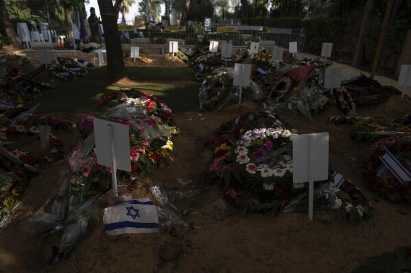 An Israeli flag lays next to flowers on a grave of a soldier killed in the Israel-Hamas war at Mount Herzl military cemetery, in Jerusalem, Monday, Oct. 16, 2023. (AP Photo/Petros Giannakouris)