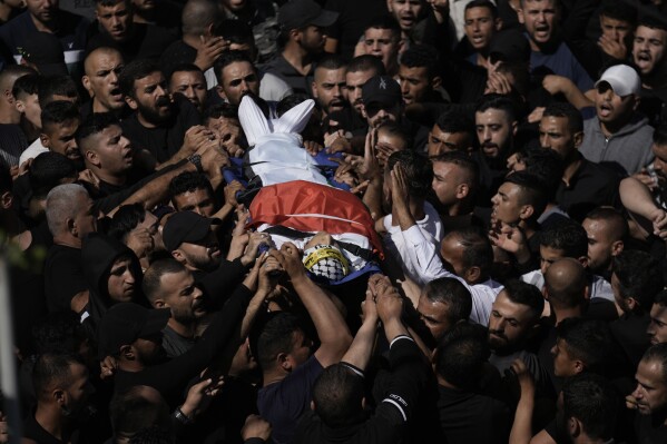 Palestinian mourners carry the body of Oday Mansour, 17, during his funeral in the West Bank village of Kafr Qallil, Saturday, Oct. 21, 2023. Mansour was killed in clashes with Israeli forces Friday during a protest in support of the Gaza Strip, at a military checkpoint in the flash point town of Hawara, West Bank. (AP Photo/Majdi Mohammed)