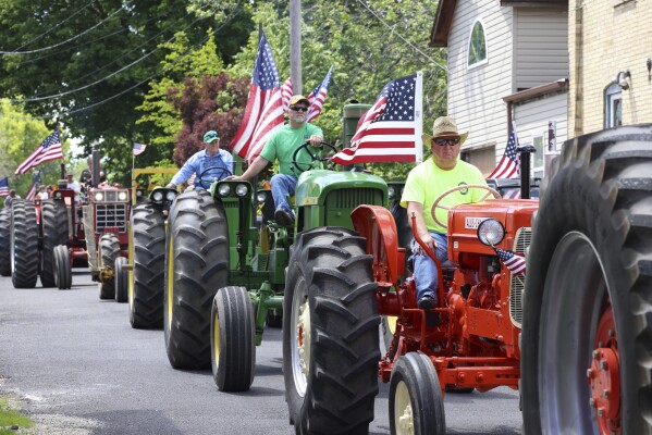 Children watch tractors in a parade in Waubeka, Wis., on June 9, 2024. Old Glory is venerated annually in Waubeka, the small town that lays claim to the first Flag Day. (AP Photo/Teresa Crawford)