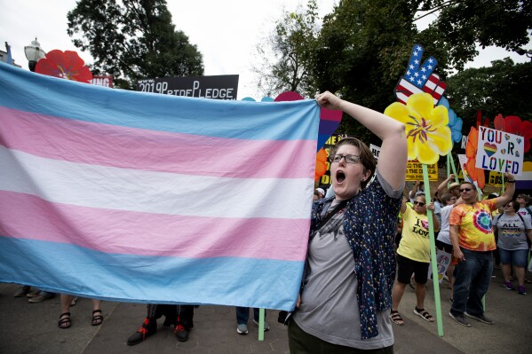 FILE - A supporter holds a transgender flag at the Gay Pride Festival in Atlanta on Oct. 12, 2019. Georgia senators are proposing further restrictions on gender-affirming care for minors, including a ban on prescribing puberty blocking drugs for most people under 18. (AP Photo/Robin Rayne, file)
