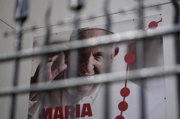 A poster showing a picture of Pope Francis and announcing World Youth Day 2023 hangs outside a church in Lisbon, Tuesday, July 25, 2023. Pope Francis is going on a five-day visit next week to Portugal, where a scandal that erupted earlier this year over Catholic Church sex abuse is still simmering, to attend international World Youth Day. (AP Photo/Armando Franca)
