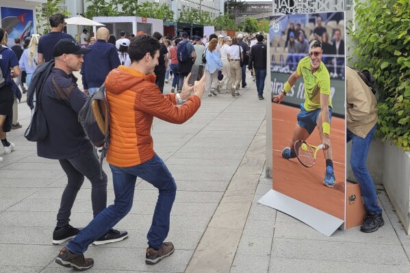 A French fan poses with a life-sized cardboard cutout of Rafael Nadal next to Roland Garros main stadium, Tuesday, May 21, 2024 in Paris. The French Open tennis tournament start Sunday May 26th. (AP Photo/Tom Nouvian)