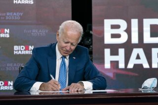 Democratic presidential candidate former Vice President Joe Biden signs a required documents for receiving the Democratic nomination for President of the United States in Wilmington, Del., Friday, Aug. 14, 2020. (AP Photo/Carolyn Kaster)