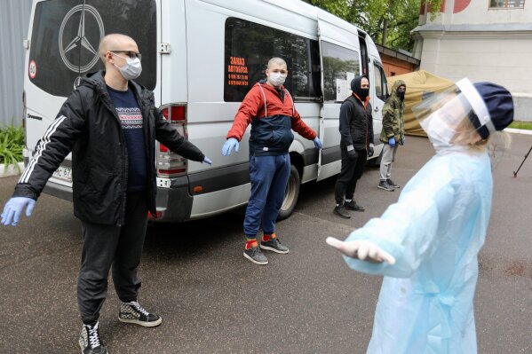 A group of conscripts, wearing face masks to protect against coronavirus, stand during a medical checkup at a military conscription office in Moscow, Russia, Friday, May 22, 2020. The Russian military has launched a regular draft despite the coronavirus pandemic. (Kirill Zykov, Moscow News Agency photo via AP)