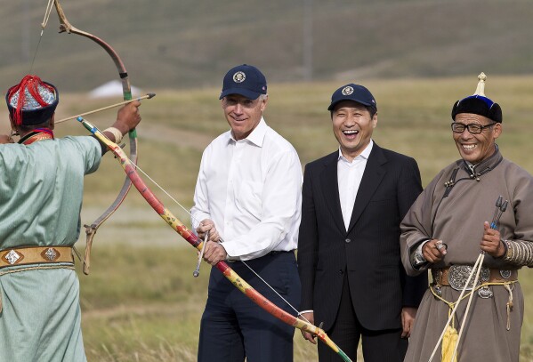 U.S. Vice President Joe Biden, center left, accompanied by Mongolian Prime Minister Sukhbaatar Batbold, center right, tries out an archery during their tour at Mini Nadam or Mongolian wrestling performance in Ulan Bator, Mongolia, Monday, Aug. 22, 2011. (AP Photo/Andy Wong)