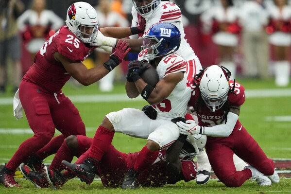 Arizona Cardinals safety Andre Chachere, right tackles New York Giants running back Saquon Barkley (26) during the first half of an NFL football game, Sunday, Sept. 17, 2023, in Glendale, Ariz. (AP Photo/Matt York)
