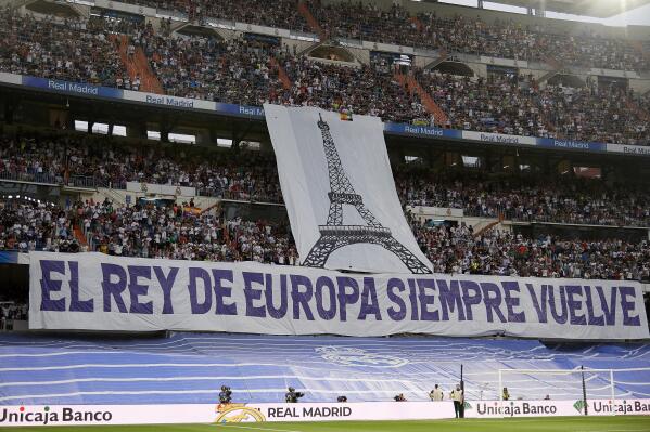 Fans of Real Madrid hold a banner referring to the upcoming Champions League final prior to a Spanish La Liga soccer match between Real Madrid and Betis at the Santiago Bernabeu stadium in Madrid, Spain, Friday, May 20, 2022. (AP Photo/Jose Breton)