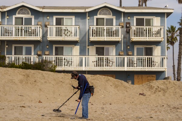 Metal detectorist Josh Snider searches for metals on the edge of the beach ahead of a storm outside the boarded-up Inn on the Beach hotel in Ventura, Calif., Wednesday, Jan. 31, 2024.(AP Photo/Damian Dovarganes)