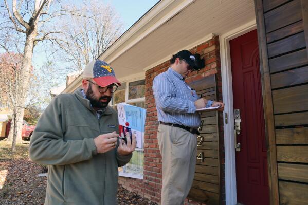 City council candidates Democrat Joe Solomon, right, and Republican Frank Annie stop to leave pamphlets at a house while canvassing, Sunday, Oct. 23, 2022, in Charleston, W.Va. (AP Photo/Leah Willingham)