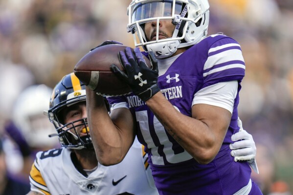 Northwestern defensive back Theran Johnson, right, intercepts a pass intended for Iowa wide receiver Nico Ragaini, left, during the first half of an NCAA college football game Saturday, Nov. 4, 2023, at Wrigley Field in Chicago. (AP Photo/Erin Hooley)