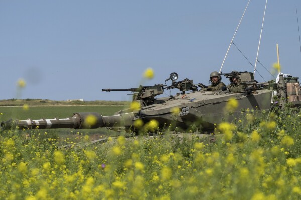 Israeli soldiers move on the top of a tank near the Israeli-Gaza border, as seen from southern Israel, Thursday, March 21, 2024. (AP Photo/Ohad Zwigenberg)