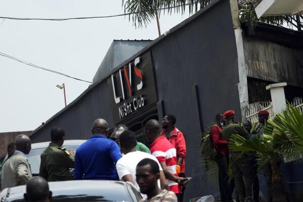 Police officers and officials stand outside the Livs Night Club in Yaounde, Cameroon, Sunday, Jan. 23, 2022. A fire erupted at a popular nightclub in Cameroon's capital, setting off explosions and killing at least 16 people, government officials said Sunday. (AP Photo/Themba Hadebe)