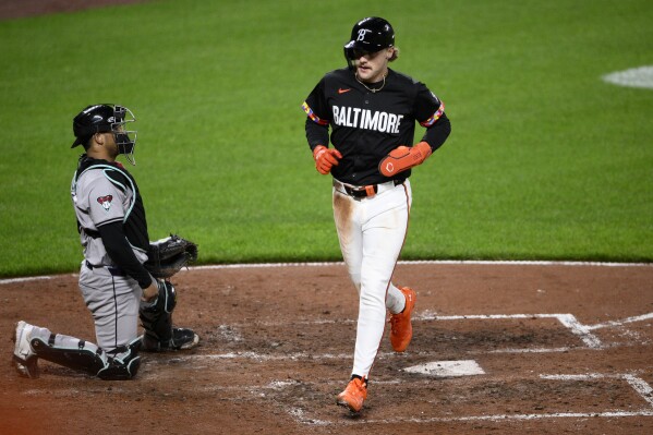 Baltimore Orioles' Gunnar Henderson, right, scores on a single by Ryan O'Hearn, next to Arizona Diamondbacks catcher Gabriel Moreno during the fifth inning of a baseball game Friday, May 10, 2024, in Baltimore. (AP Photo/Nick Wass)