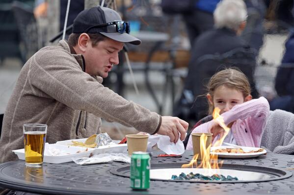 Eden Maracco, 8, has lunch her dad Jeffery while power is out at her home, at Reds Food Truck Corner in Southern Pines, N.C., Monday, Dec. 5, 2022. Tens of thousands of people braced for days without electricity in a North Carolina county where authorities say two power substations were shot up by one or more people with apparent criminal intent. (AP Photo/Karl B DeBlaker)