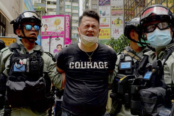 Police detain a protester after spraying pepper spray during a protest in Causeway Bay before the annual handover march in Hong Kong, Wednesday, July. 1, 2020. Hong Kong marked the 23rd anniversary of its handover to China in 1997, and just one day after China enacted a national security law that cracks down on protests in the territory. (AP Photo/Vincent Yu)