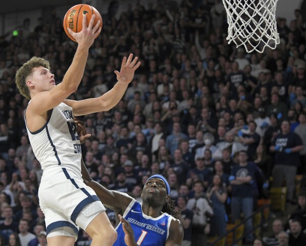 El guardia del estado de Utah, Mason Falslev (12), conduce hacia la canasta mientras el delantero del estado de Boise, O'Mar Stanley (1), defiende durante la segunda mitad de un partido de baloncesto universitario de la NCAA el sábado 10 de febrero de 2024 en Logan, Utah.  (Eli Lucero/Herald Journal vía AP)/The Herald Journal vía AP)