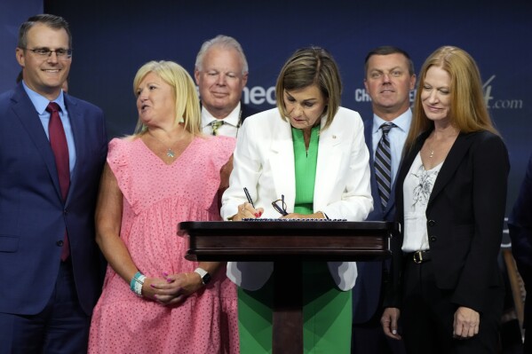 Iowa Gov. Kim Reynolds signs a new law banning abortions after six weeks of pregnancy before speaking at the Family Leadership Summit, Friday, July 14, 2023, in Des Moines, Iowa. (AP Photo/Charlie Neibergall)