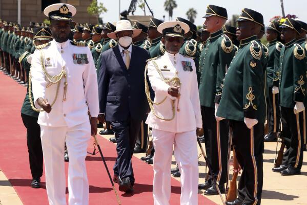 Ugandan President Yoweri Museveni, centre, wearing a mask, inspects a guard of honour during a welcoming ceremony in Pretoria, South Africa, Tuesday, Feb. 28, 2023. Museveni's visit is directed at consolidating bilateral relations between the two countries, with discussions between the two Heads of State encompassing political, economic, regional, continental and international issues. (AP Photo)
