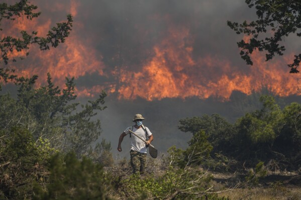 Flames burn a forest in Vati village, on the Aegean Sea island of Rhodes, southeastern Greece, on Tuesday, July 25, 2023. A third successive heat wave in Greece pushed temperatures back above 40 degrees Celsius (104 degrees Fahrenheit) across parts of the country Tuesday following more nighttime evacuations from fires that have raged out of control for days. (AP Photo/Petros Giannakouris)