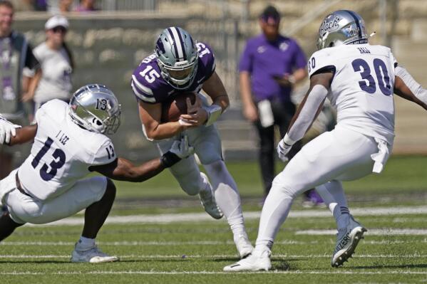 Kansas State quarterback Will Howard (15) runs between Nevada defensive back Jordan Lee (13) and linebacker Lawson Hall (30) during the first half of an NCAA college football game Saturday, Sept. 18, 2021, in Manhattan, Kan. (AP Photo/Charlie Riedel)