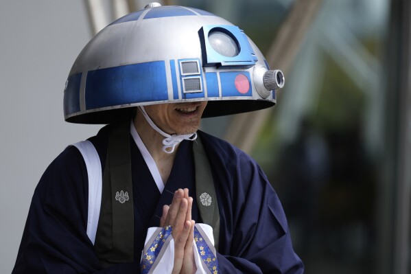 A Star Wars fan in an R2-D2 costume poses for a photo outside the venue during a fan convention called the Star Wars Celebration in Chiba, near Tokyo, Friday, April 18, 2025. (AP Photo/Hiro Komae)