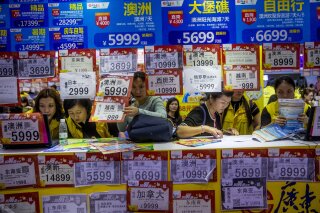 
              In this March 3, 2018, photo, people check on travel packages offered by travel agencies during the Guangzhou International Travel Fair in Guangzhou in south China's Guangdong province. Travelers in China were blocked from buying plane tickets 17.5 million times last year as a penalty for failing to pay fines or other offenses. The Chinese government reported this week on penalties imposed under a controversial "social credit" system the ruling Communist Party says will improve public behavior. (Chinatopix via AP)
            