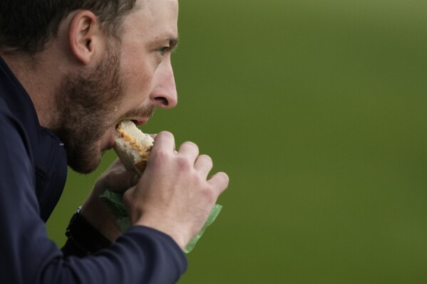 A patron eats a pimento cheese sandwich during a practice round in preparation for the Masters golf tournament at Augusta National Golf Club Tuesday, April 9, 2024, in Augusta, Ga. (AP Photo/Charlie Riedel)