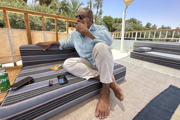 Ibn Sina Mansour, a Sudanese-British national, waits for a call from his older brother, al-Samual Mansour, who is trapped in Sudan, at his hotel in Aswan, Egypt, on May 10, 2023. Ibn Sina traveled to Aswan to be close to his brother, who lost his travel documents and is unable to cross into Egypt. (AP Photo/Samy Magdy)