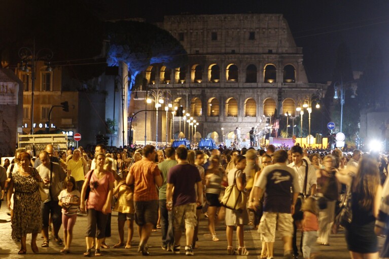 People gather at the Fori Imperiali avenue, with the Colosseum in the background, during an event celebrating the ban on private vehicles, in Rome, Saturday, Aug. 3, 2013. The Vatican crosses a key milestone Thursday, May 9, 2024, in the run-up to its 2025 Jubilee with the promulgation of the official decree establishing the Holy Year: a once-every-quarter-century event that is expected to bring some 32 million pilgrims to Rome and has already brought months of headaches to Romans. (AP Photo/Riccardo De Luca)
