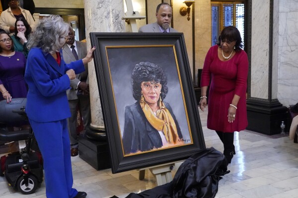 Former Mississippi State Rep. Alyce Clarke, D-Jackson, left, artist Ryan Mack of Jackson, center, and Marilyn Luckett, president of Connecting the Dots Foundation, unveil Clarke's official portrait in the Mississippi State Capitol in Jackson, Tuesday, Feb. 13, 2024. Clarke, a long time legislator, is the first woman and the first African American to have a portrait displayed in the state Capitol. (AP Photo/Rogelio V. Solis)