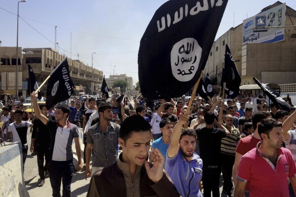 FILE - Demonstrators chant pro-Islamic State group slogans as they carry the group's flags in front of the provincial government headquarters in Mosul, Iraq, June 16, 2014. The Islamic State group announced Thursday the death of its little known leader Abu al-Hussein al-Husseini al-Qurayshi who had been heading the extremist organization since November. (AP Photo, File)