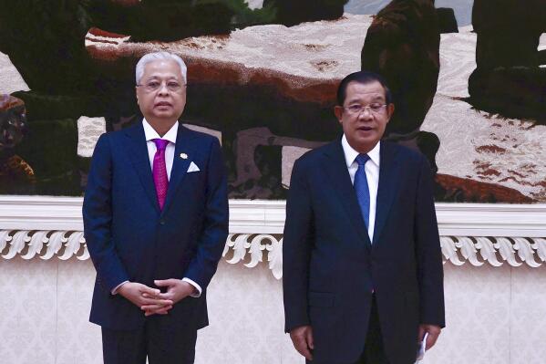 In this photo provided by Kok Ky/Cambodia's Government Cabinet, Cambodian Prime Minister Hun Sen, right, poses for photographs together with his Malaysian counterpart Ismail Sabri Yaakob, left, during his visit to Cambodia in Phnom Penh, Cambodia, Thursday, Feb. 24, 2022. (Kok Ky/Cambodia's Government Cabinet via AP)
