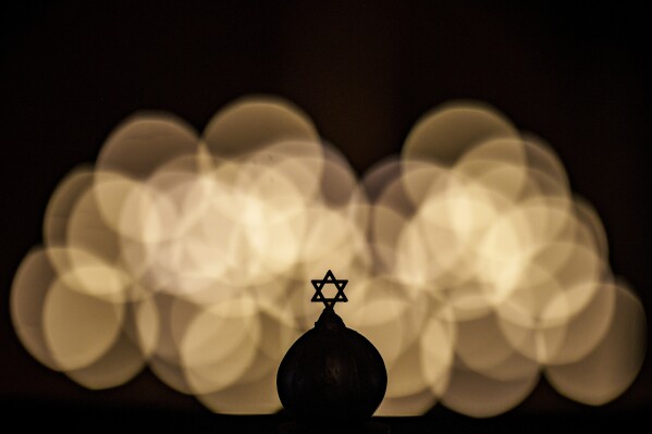 The Star of David is silhouetted against light installations during a memorial for the victims of the Holocaust, at the Coral Temple synagogue in Bucharest, Romania, Monday, Jan. 29, 2024. (AP Photo/Andreea Alexandru)