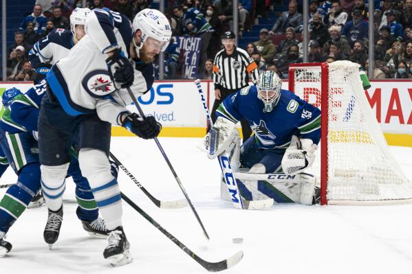 Winnipeg Jets' Pierre-Luc Dubois, left, puts a backhand shot on Vancouver Canucks goalie Thatcher Demko during the third period of an NHL hockey game Friday, Nov. 19, 2021, in Vancouver, British Columbia. (Rich Lam/The Canadian Press via AP)