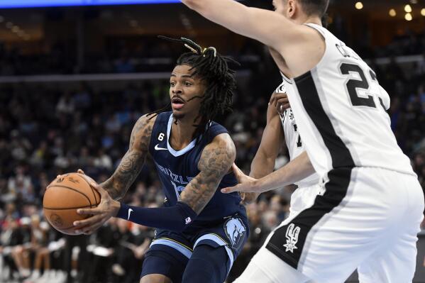 Memphis Grizzlies guard Ja Morant (12) is defended by San Antonio Spurs center Jakob Poeltl (25) and another Spur during the first half of an NBA basketball game Wednesday, Jan. 11, 2023, in Memphis, Tenn. (AP Photo/Brandon Dill)
