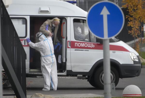 A medical worker helps a patient suspected of having coronavirus to leave an ambulance at a hospital in Kommunarka, outside Moscow, Russia, Tuesday, Oct. 12, 2021. Russia hit another record of daily coronavirus deaths Tuesday as the country struggled with a rapid surge of infections and lagging vaccination rates, but authorities have been adamant that there would be no new national lockdown. (AP Photo/Alexander Zemlianichenko)