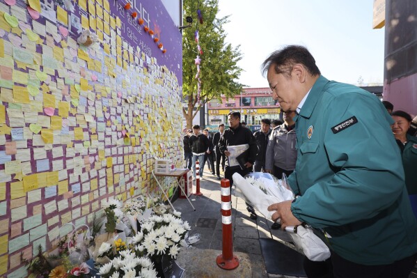South Korean Interior and Safety Minister Lee Sang-min places flowers to pay his condolence to the victims of the Oct. 29, 2022 crush, in front of the messages for victims in Seoul, South Korea, Saturday, Oct. 28, 2023. South Koreans are holding highly subdued Halloween celebrations this weekend amid tight police security, as the country marks the first anniversary of the harrowing party crush that killed about 160 people.(Shin Hyun-woo/Yonhap via AP)