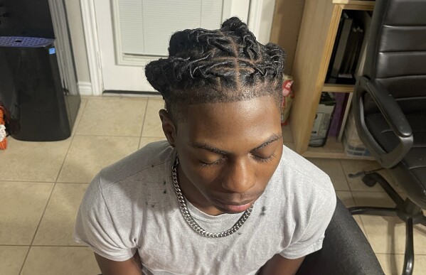 In this photo provided by Darresha George, her son Darryl George, 17, a junior at Barbers Hill High School in Mont Belvieu, Texas, sits for a photo showing his locs, at the family's home, Sept. 10, 2023. The same week a state law went into effect prohibiting discrimination on the basis of hair, George was suspended because his locs did not comply with the district's dress code. (Darresha George via AP)
