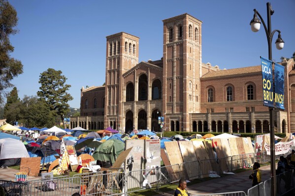 Pro-Palestinian protesters continued to occupy the grounds of the University of California, Los Angeles, in front of Royce Hall, Monday, April 29, 2024, in Los Angeles.  Security forces surrounded the camp after a skirmish broke out on Sunday between pro-Palestinian protesters and supporters of Israel.  (David Crane/The Orange County Register via AP)