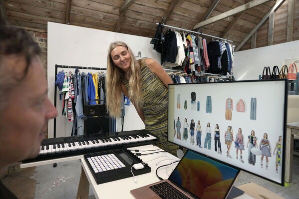 Ksenia Schnaider, a Ukrainian fashion designer, center, chats with her husband Anton Schnaider at their studio in Haywards Heath, West Sussex, England, Thursday, Sept. 14, 2023. For Ksenia Schaider and other Ukrainian designers, the fashion show must go on, despite the war in their country – or precisely because of it. Schaider may have fled to the U.K. as a refugee, but her team still makes every garment in Kiev, often under incessant air raid sirens and lengthy power cuts. (AP Photo/Kin Cheung)